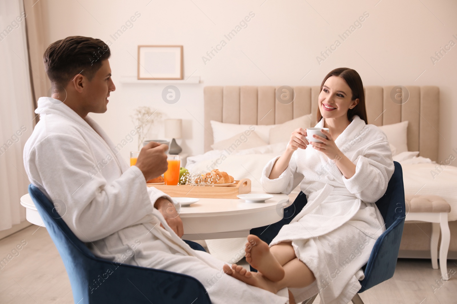 Photo of Happy couple in bathrobes having breakfast at home