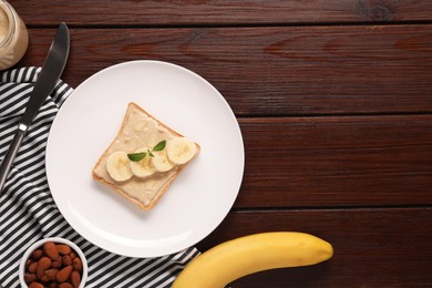 Photo of Toast with tasty nut butter, banana slices and almond flakes on wooden table, flat lay. Space for text