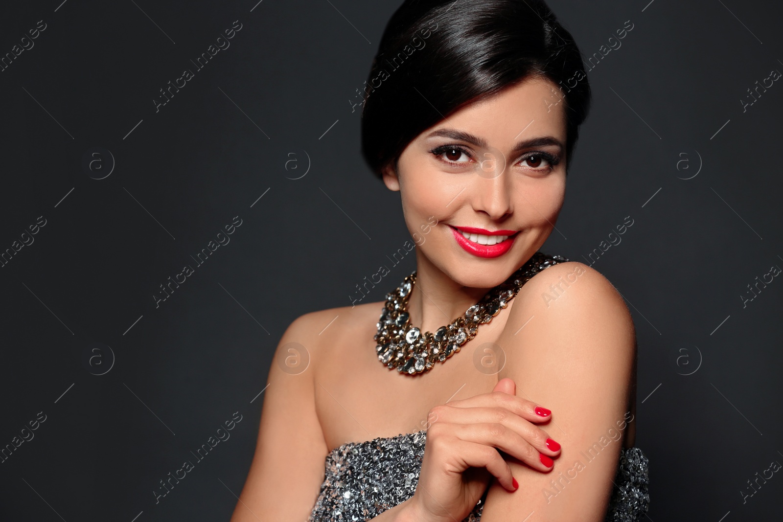 Photo of Beautiful young woman with elegant jewelry on dark background. Space for text