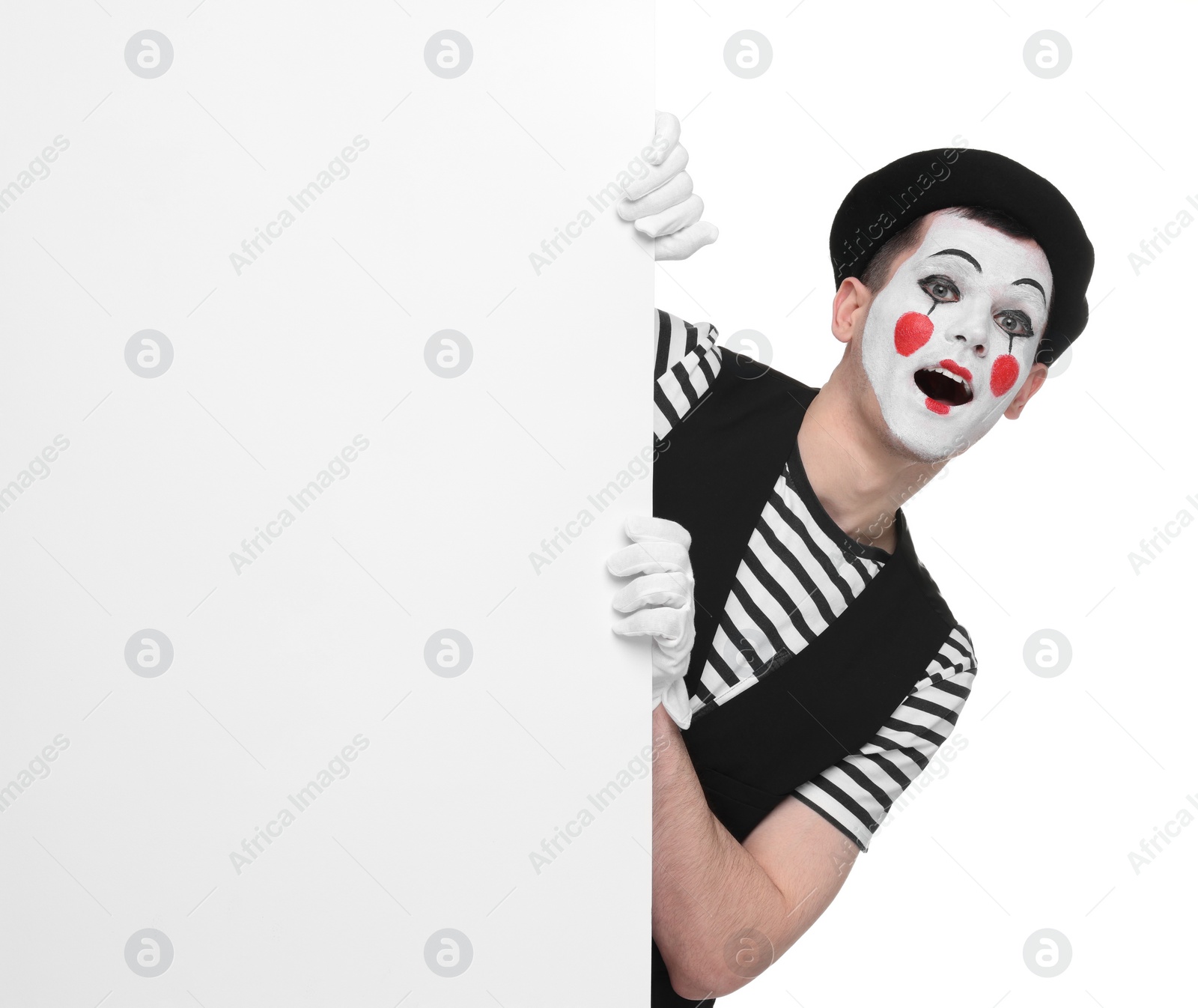 Photo of Funny mime artist peeking out of blank poster on white background