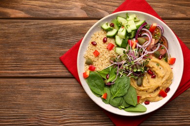 Delicious vegan bowl with cucumbers, spinach and bulgur on wooden table, top view. Space for text