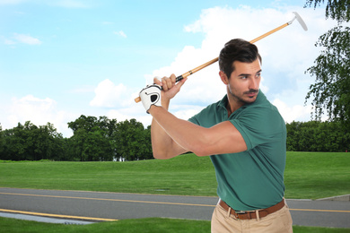 Image of Young man playing golf on course with green grass