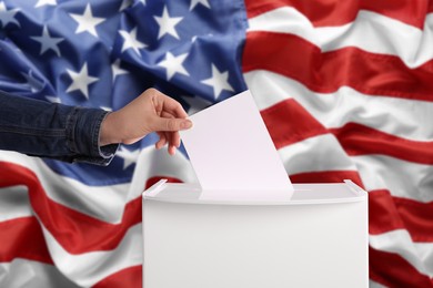 Image of Woman putting her vote into ballot box against national flag of United States, closeup