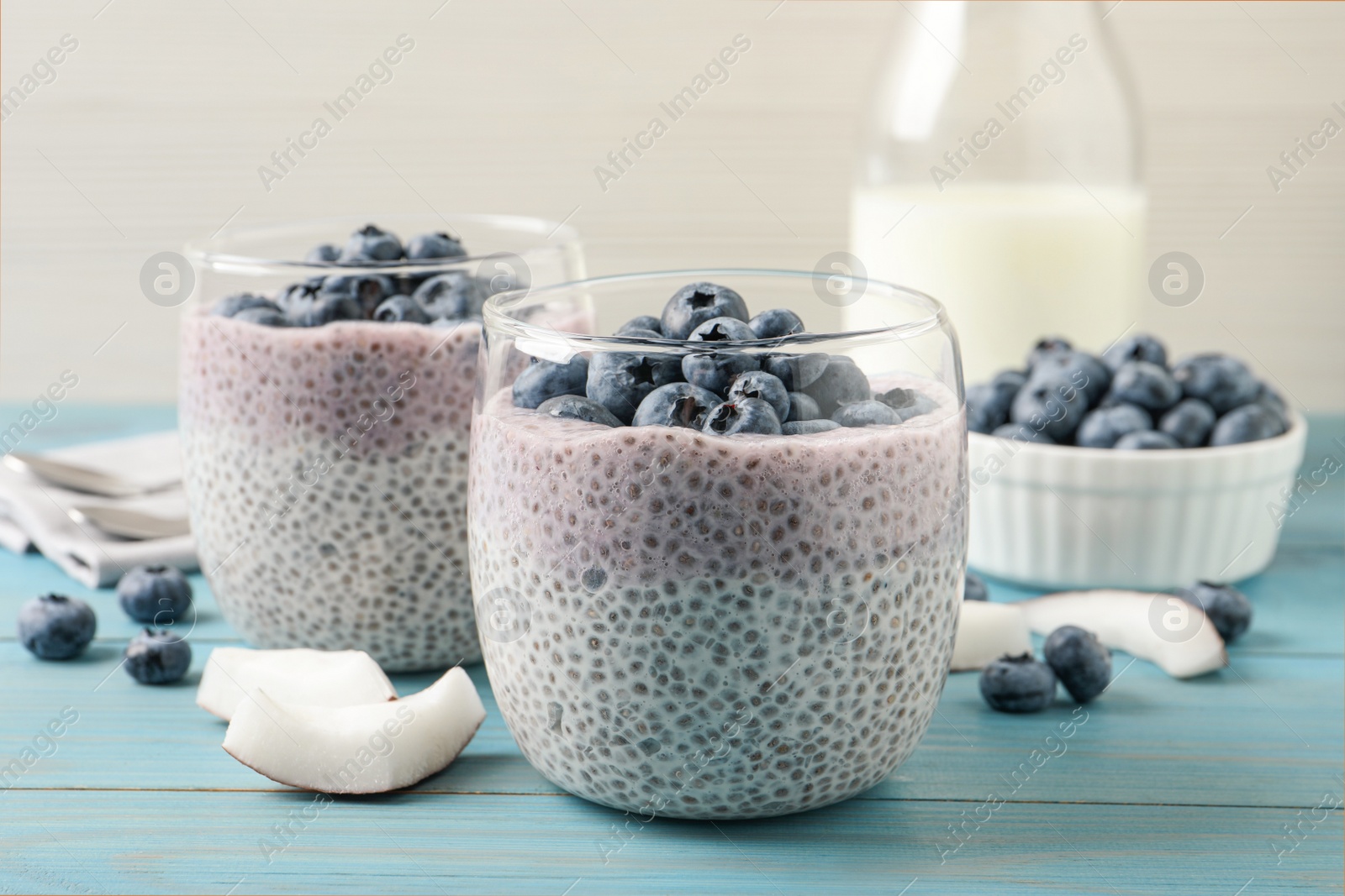 Photo of Delicious chia pudding with blueberries on light blue wooden table