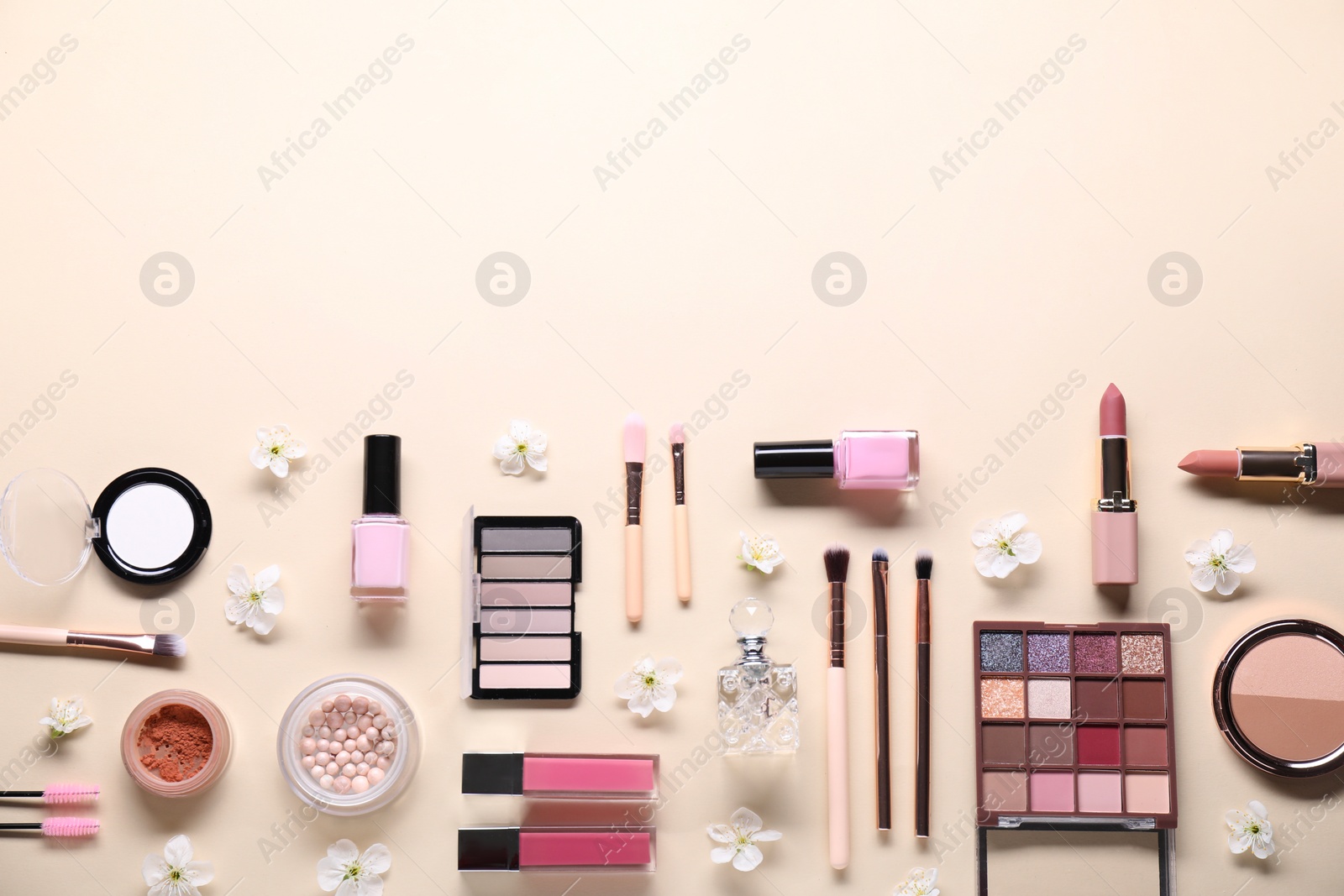 Photo of Flat lay composition with different makeup products and beautiful spring flowers on beige background, space for text