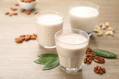 Photo of Different vegan milks and nuts on wooden table, closeup