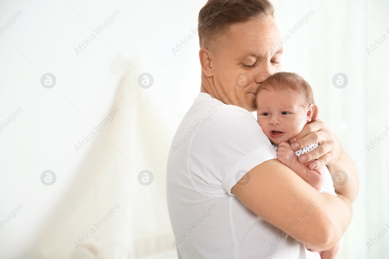 Photo of Man with his newborn baby on light background. Space for text