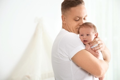 Man with his newborn baby on light background. Space for text