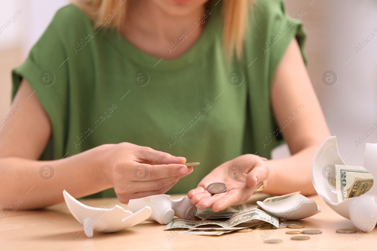 Photo of Woman with broken piggy bank and money at table, closeup