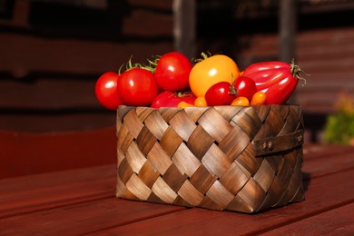 Photo of Basket with fresh tomatoes on wooden table outdoors