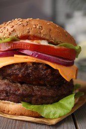 Photo of Tasty cheeseburger with patties on wooden table, closeup