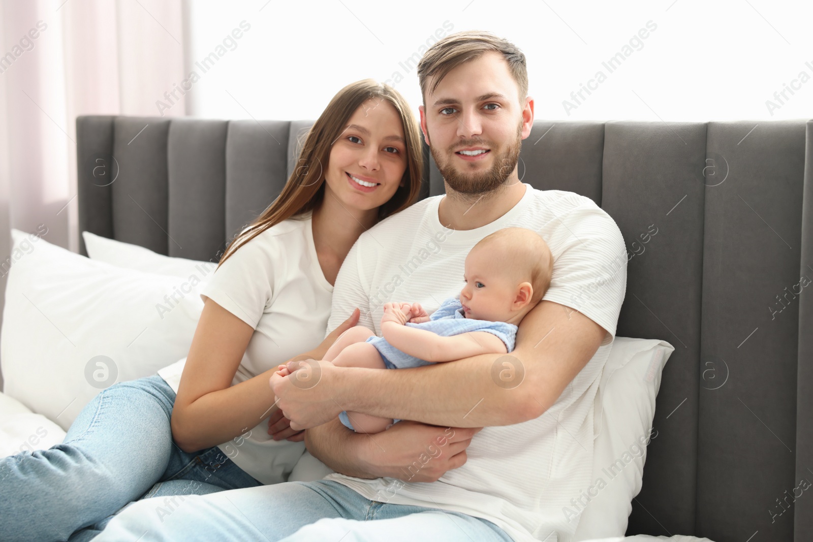 Photo of Happy family. Parents with their cute baby on bed indoors