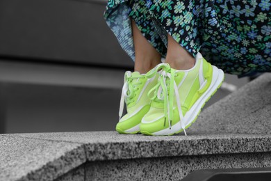 Photo of Woman wearing stylish sneakers outdoors, closeup. Space for text