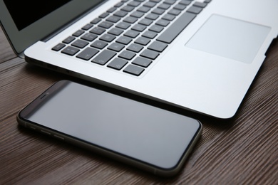 MYKOLAIV, UKRAINE - JULY 20, 2020: iPhone 11 and MacBook on wooden table, closeup