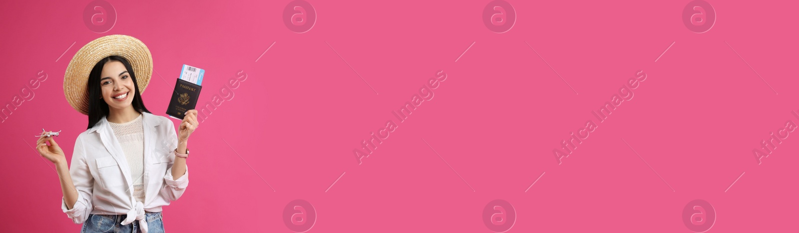 Photo of Happy female tourist with toy plane, ticket and passport on pink background. Space for text