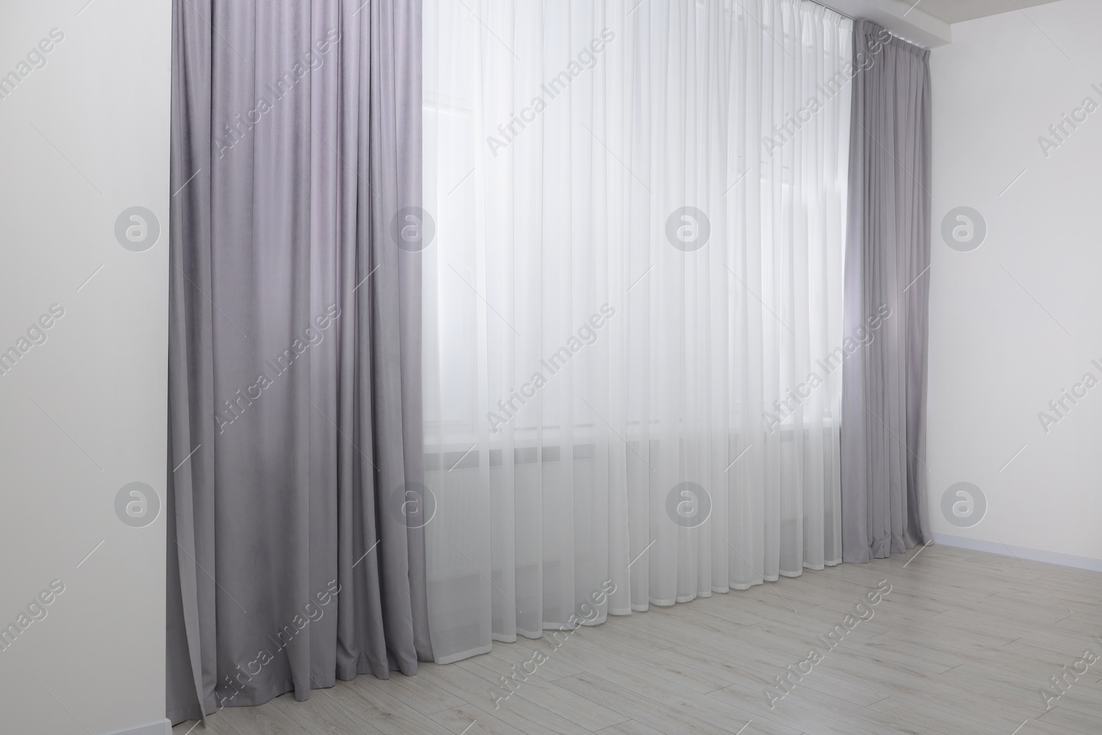 Photo of Light grey window curtains and white tulle indoors