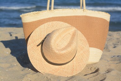 Photo of Stylish bag and hat near sea on sunny day, closeup. Beach accessories