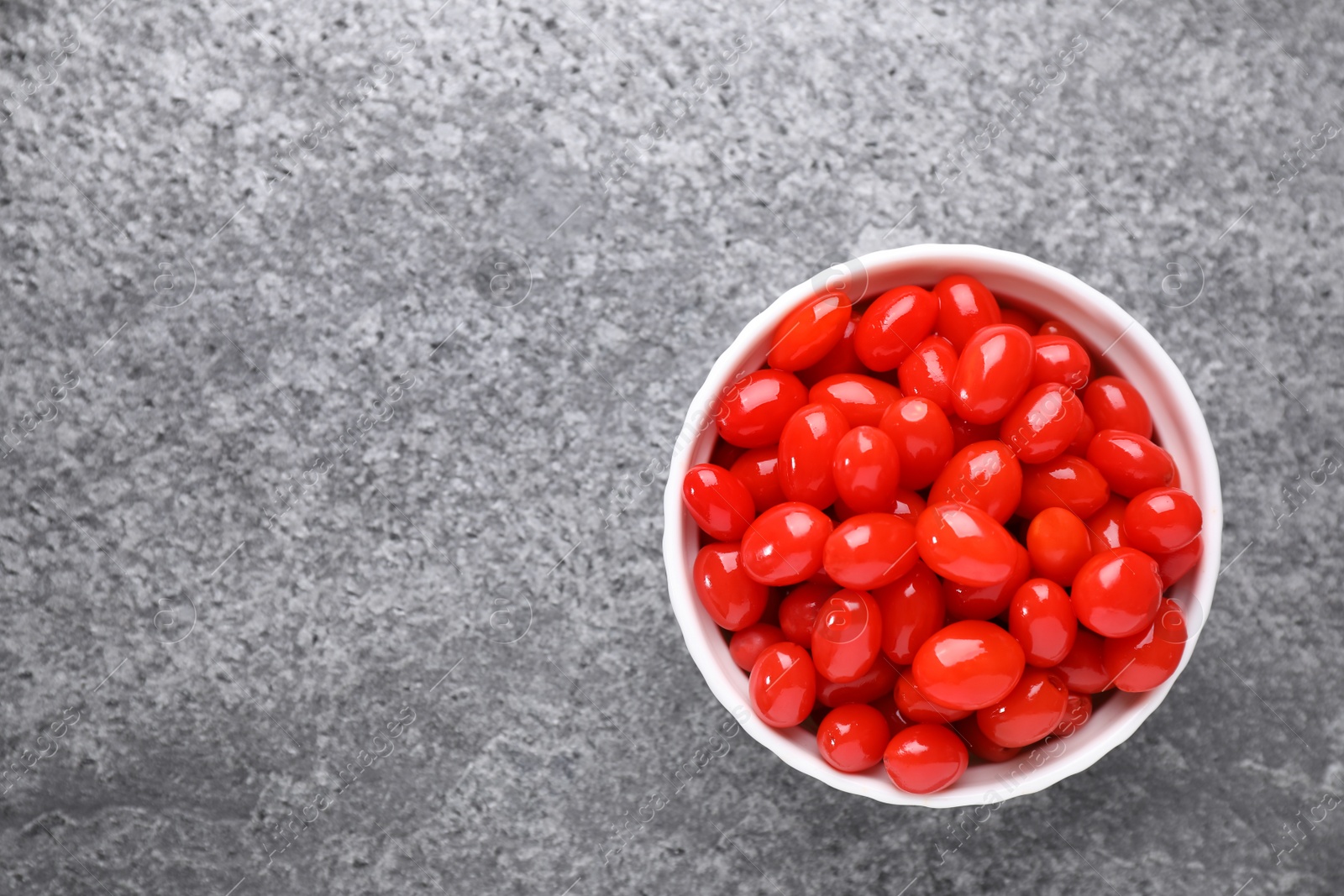 Photo of Bowl with fresh goji berries on grey background, top view. Space for text