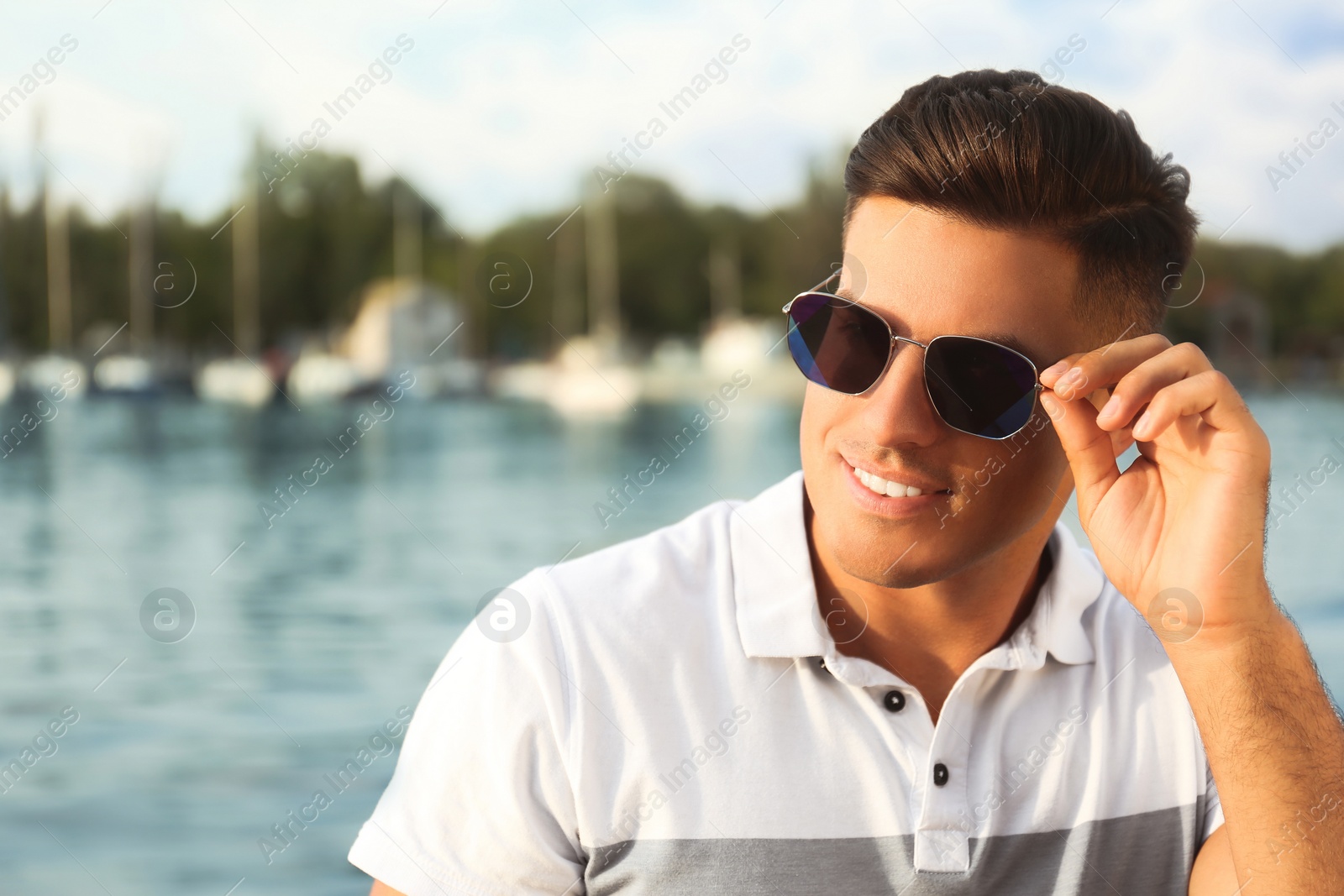 Photo of Handsome man wearing stylish sunglasses near river. Space for text