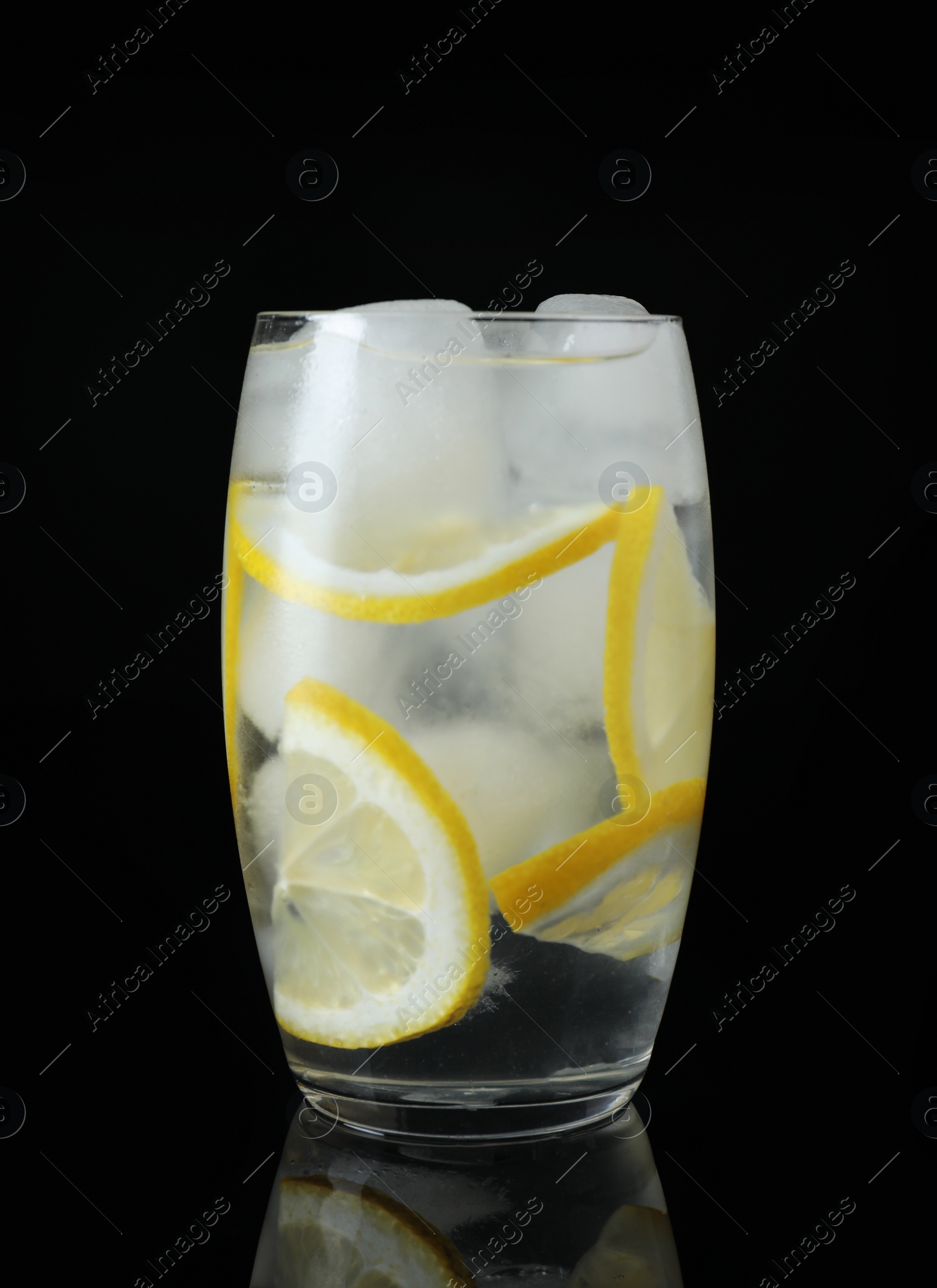 Photo of Glass of cocktail with vodka, ice and lemon on black background