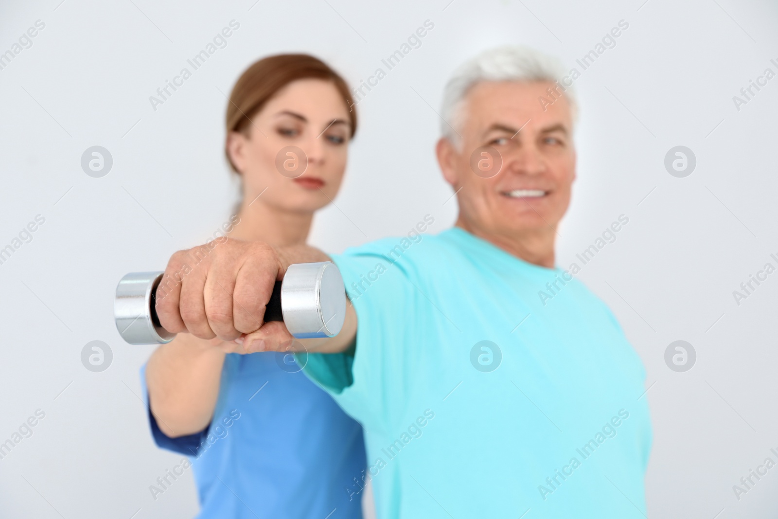 Photo of Rehabilitation physiotherapist working with senior patient against white background