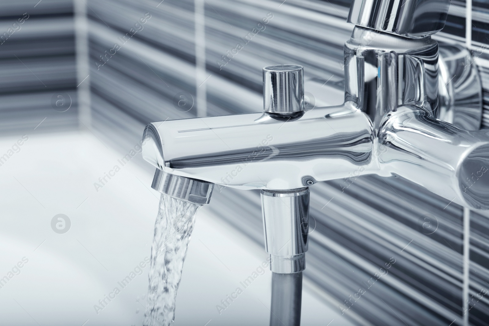 Photo of Water flowing from bath tap installed on black and white wall