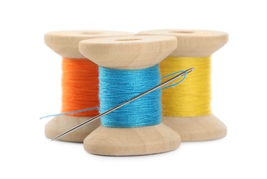 Photo of Different colorful sewing threads with needle on white background, closeup