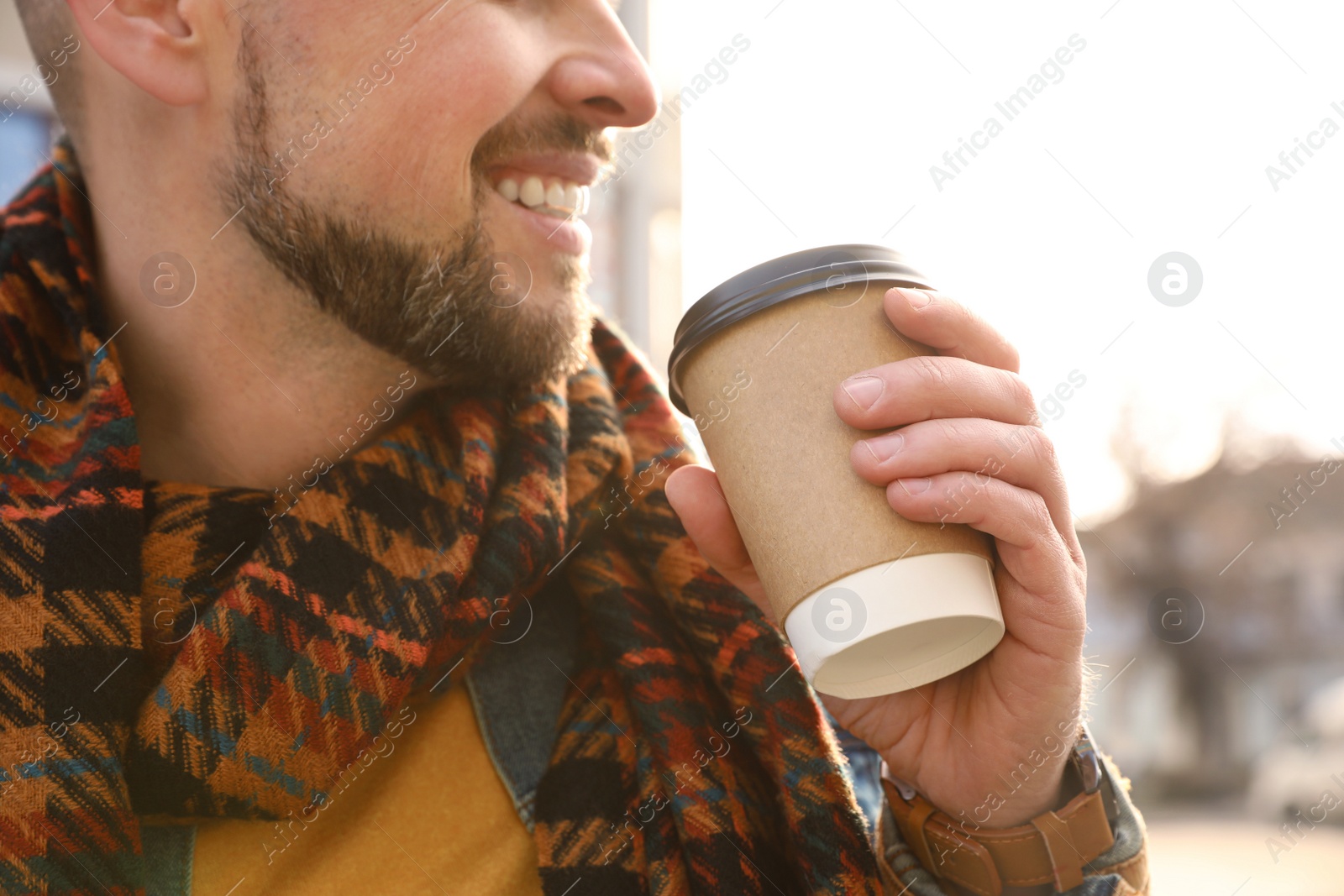 Photo of Man with cup of coffee on city street in morning, closeup