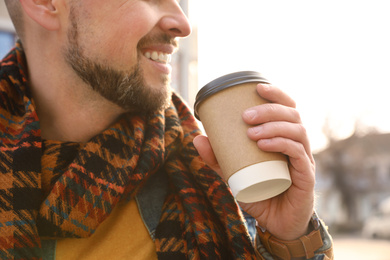 Man with cup of coffee on city street in morning, closeup