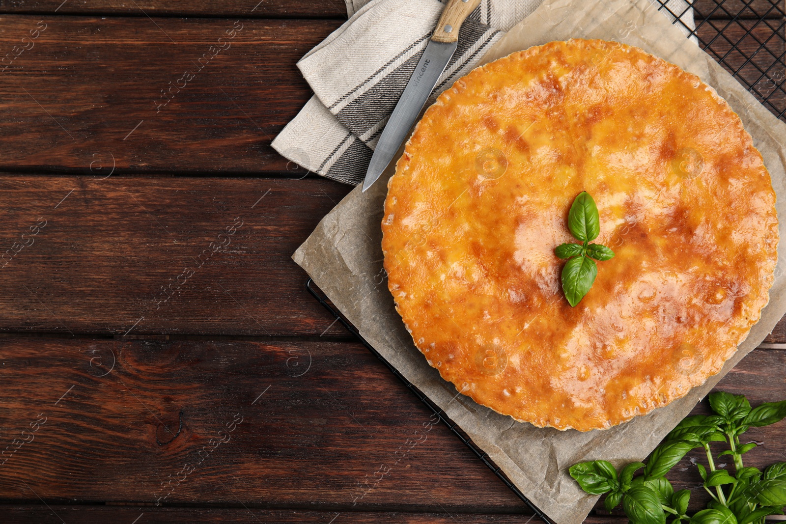 Photo of Delicious pie with meat and basil on wooden table, flat lay. Space for text