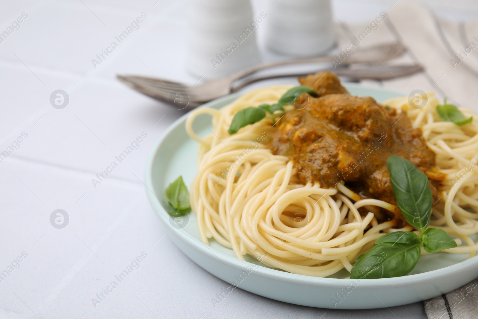 Photo of Delicious pasta and chicken with curry sauce served on white tiled table, closeup. Space for text