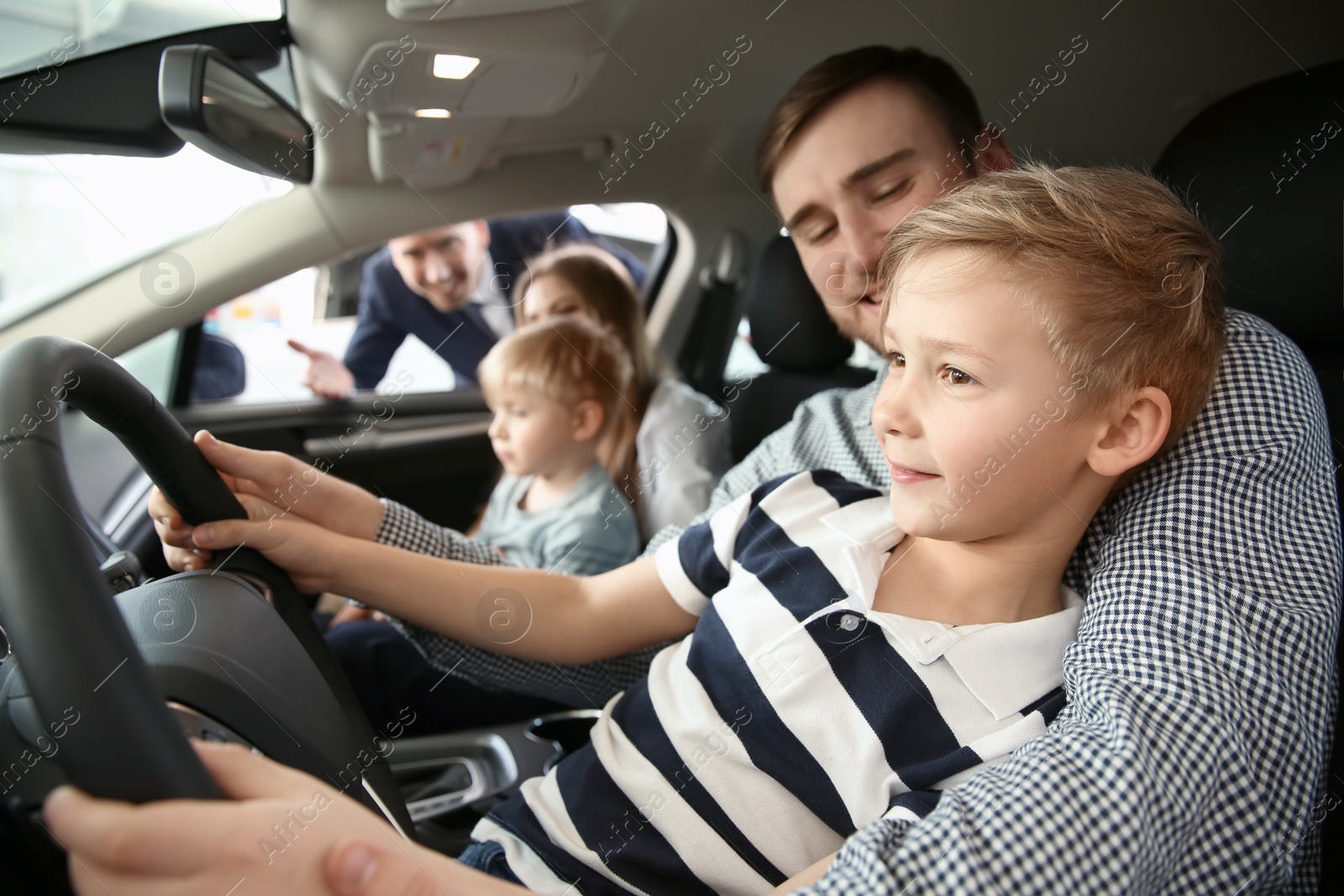 Photo of Young family choosing new car with salesman in salon