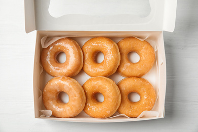 Photo of Delicious donuts on white wooden table, top view