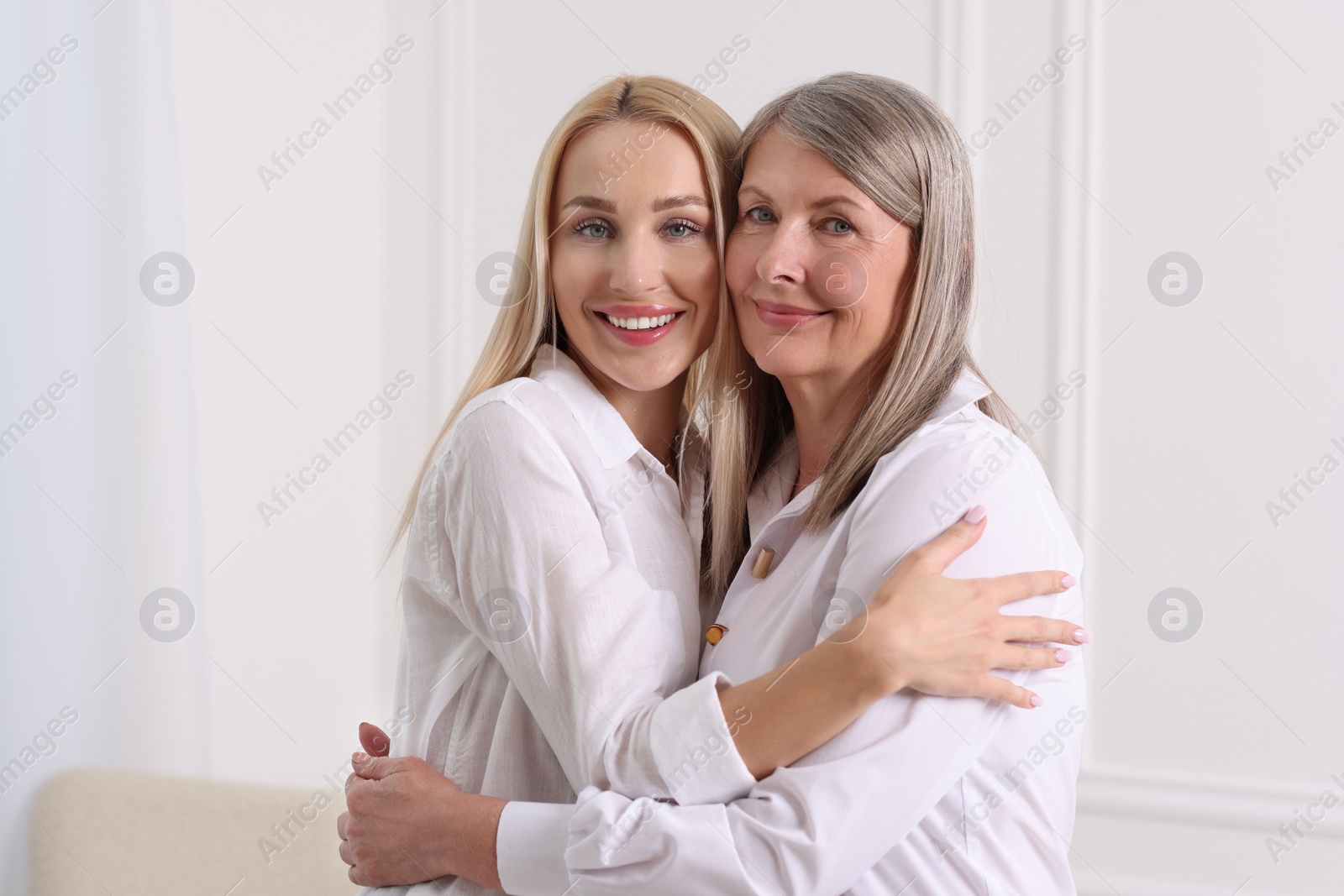 Photo of Family portrait of young woman and her mother near white wall