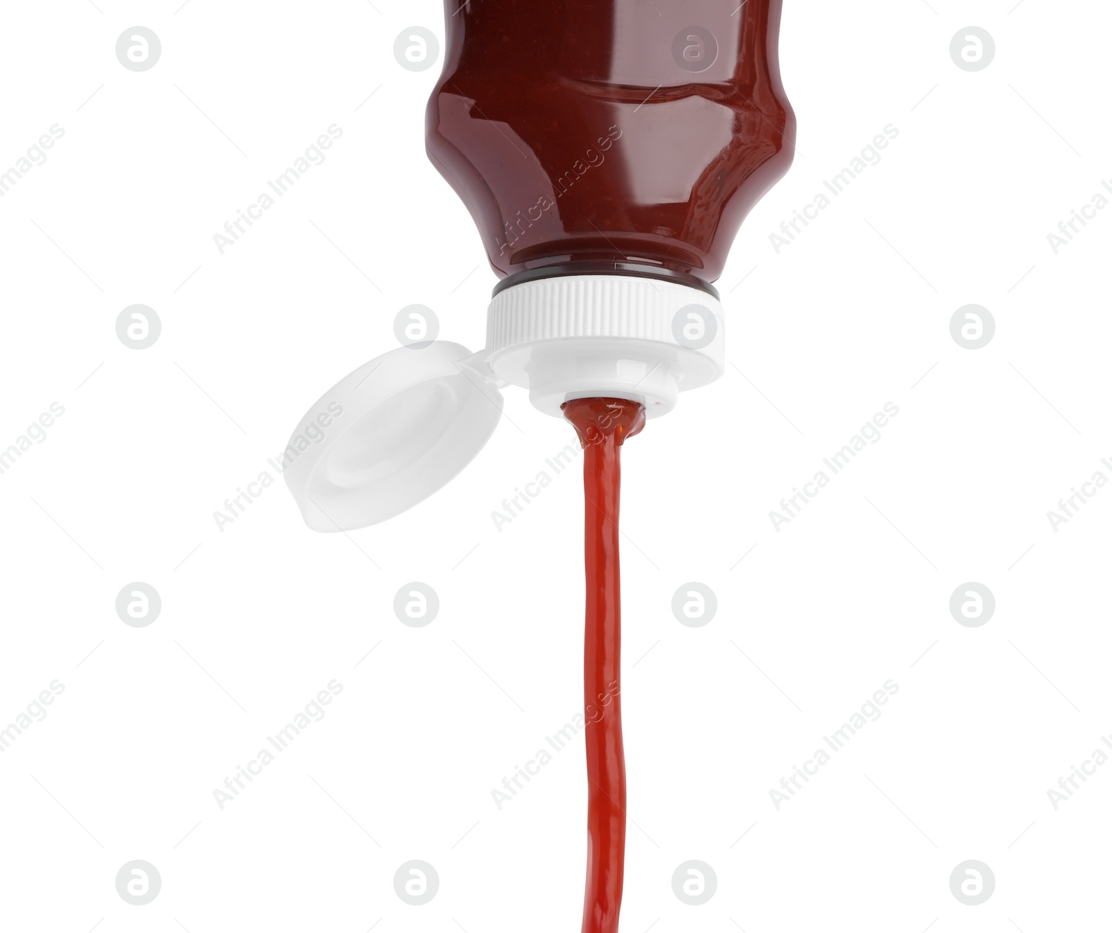 Photo of Pouring tasty red ketchup from bottle isolated on white