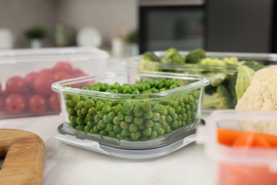 Photo of Glass container with green peas on white marble table, closeup. Food storage