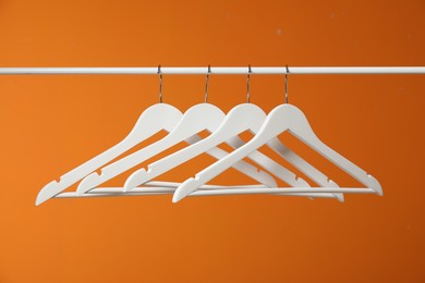 Photo of White clothes hangers on rack against orange background