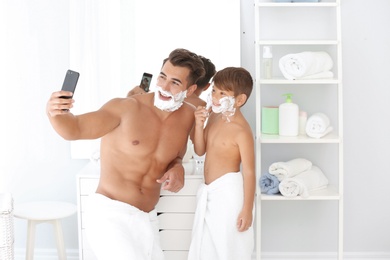 Father and son taking selfie while shaving in bathroom