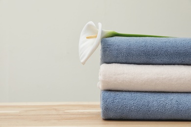 Photo of Stack of fresh towels with flower on table. Space for text