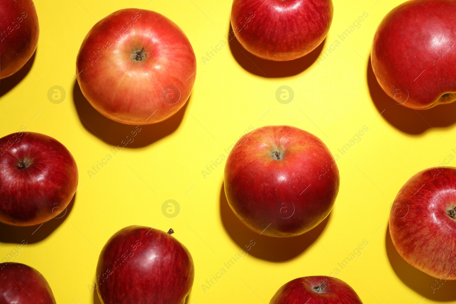 Photo of Ripe red apples on yellow background, flat lay