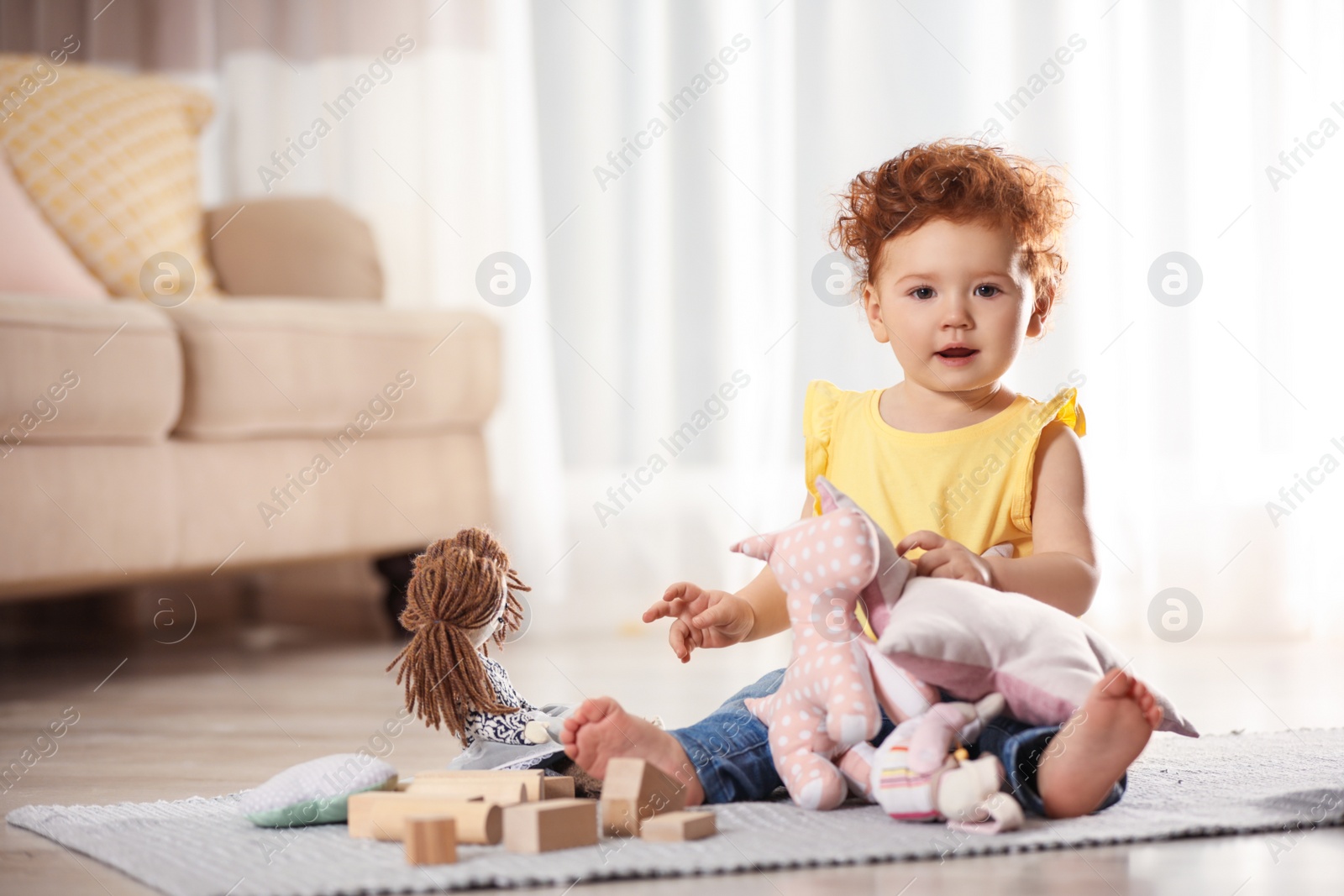 Photo of Cute little child playing with toys on floor at home