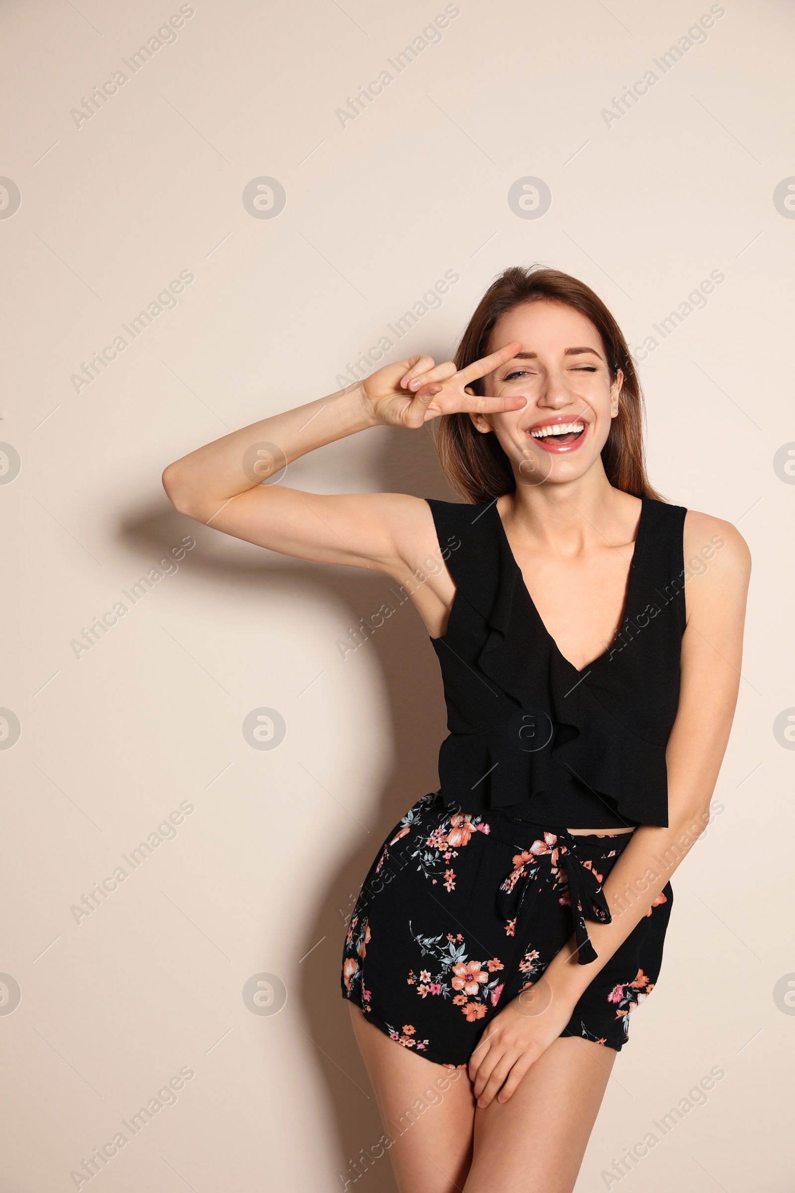 Photo of Young woman wearing floral print shorts on beige background