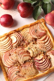 Photo of Tasty apple pie with nuts, fresh fruits and leaves on table, flat lay
