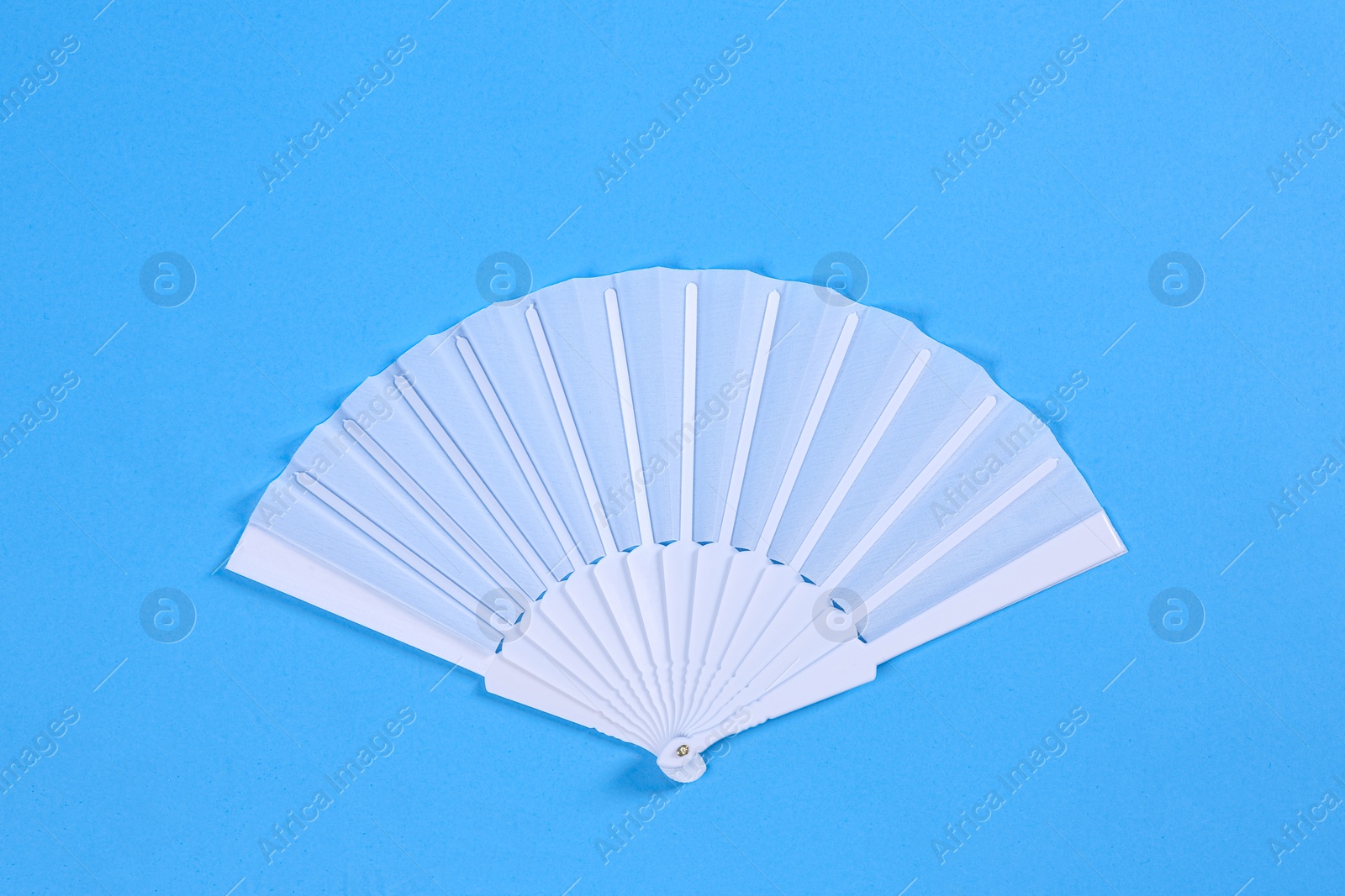 Photo of White hand fan on light blue background, top view