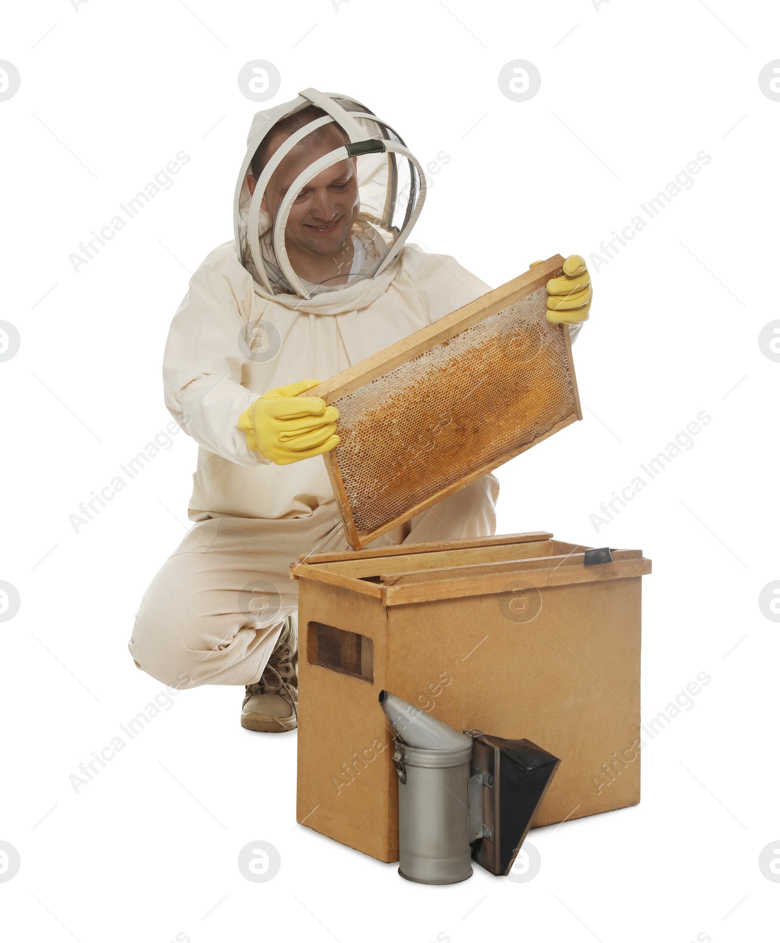 Photo of Beekeeper in uniform taking frame with honeycomb out of wooden hive on white background