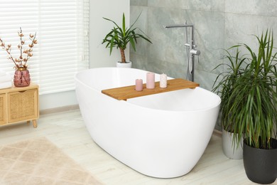 Photo of Stylish bathroom interior with beautiful tub and houseplants