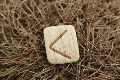 Wooden rune Kauna on dry grass outdoors, closeup