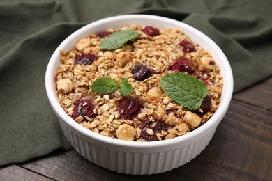 Photo of Tasty baked oatmeal with berries and nuts in bowl on wooden table, closeup