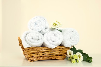 Photo of Soft folded towels and flowers on white table