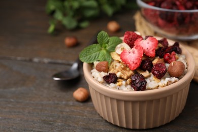 Photo of Oatmeal with freeze dried fruits, nuts and mint on wooden table, closeup. Space for text